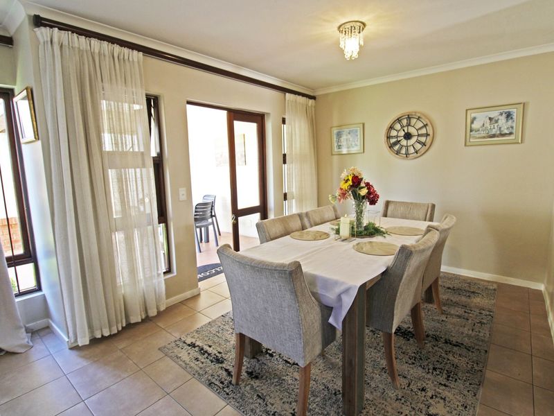 A well-lit dining room featuring tiled flooring, coved cornicing, and direct access to an outdoor patio area through a sliding glass door.