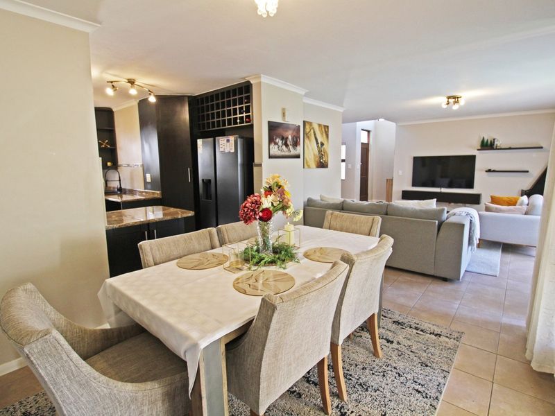 Spacious open-plan living and dining area featuring tiled floors, modern cabinetry, and a functional kitchen layout, perfect for contemporary family living.