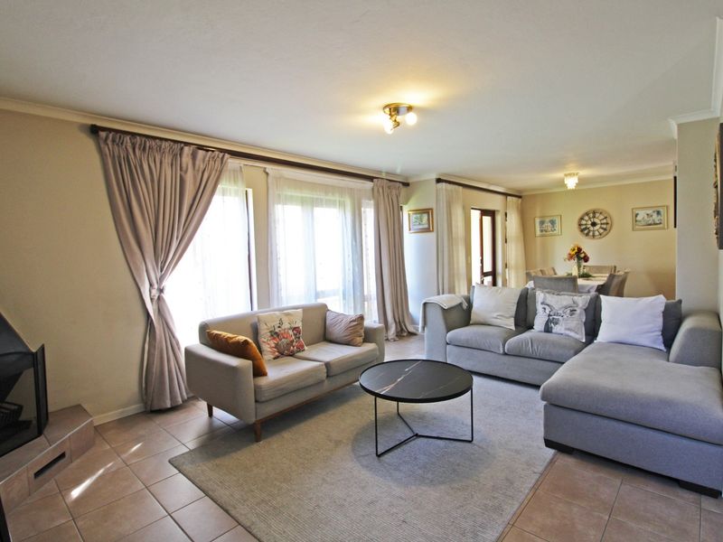 Spacious open-plan living and dining area featuring tiled flooring, a built-in fireplace, and large sliding glass doors providing ample natural light.