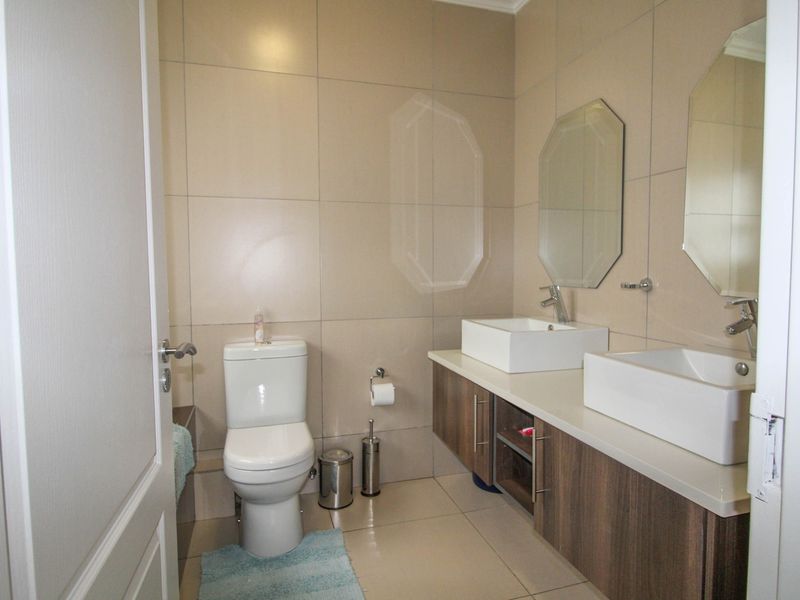 Modern bathroom featuring a double vanity with vessel sinks, wall-mounted mirrors, and neutral floor-to-ceiling wall tiles.