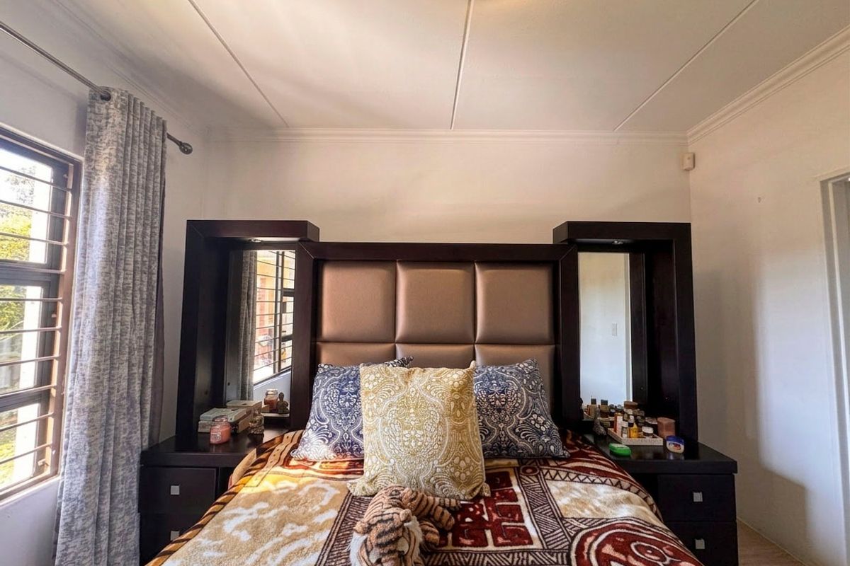A bedroom featuring a window with security bars, coved ceilings, and a central light fixture.