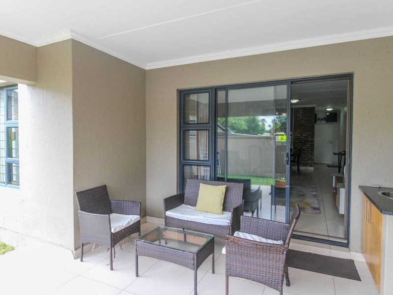 Covered patio featuring tiled flooring, a built-in kitchenette with granite countertop and sink, and sliding glass doors providing access to the interior living space.