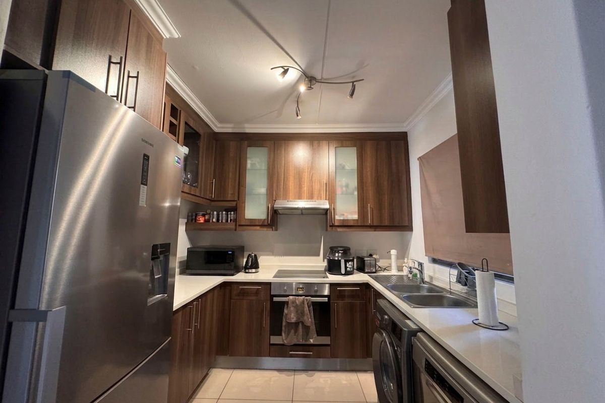 A well-maintained kitchen featuring dark wood cabinetry, stone countertops, integrated appliances, and tiled flooring, offering a functional and modern cooking space.