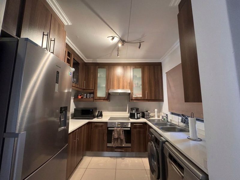 A well-maintained kitchen featuring dark wood cabinetry, stone countertops, integrated appliances, and tiled flooring, offering a functional and modern cooking space.