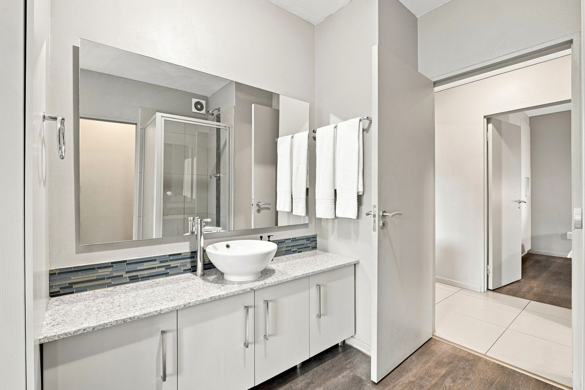 Modern bathroom featuring a vanity with granite countertop, vessel sink, large mirror, mosaic backsplash, and a separate shower enclosure.