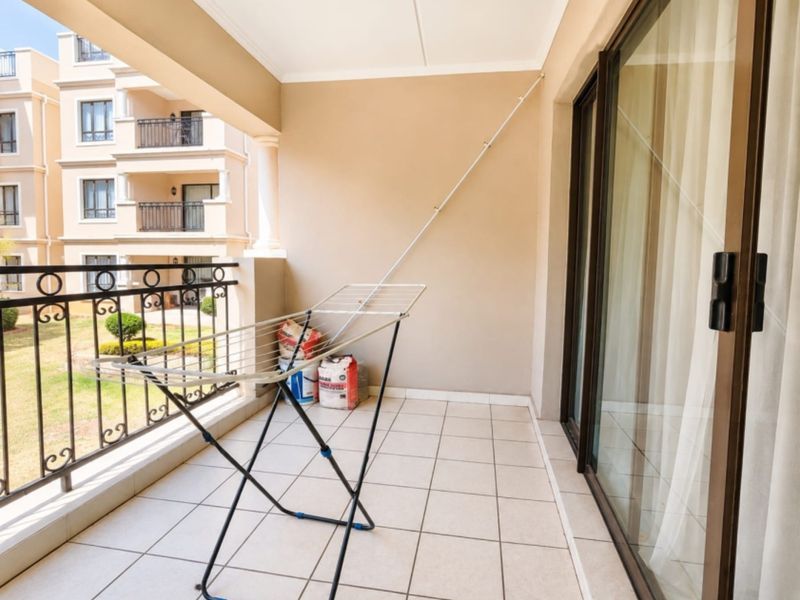 A covered balcony featuring tiled flooring and a wrought iron balustrade, offering an outdoor space accessible via sliding glass doors.