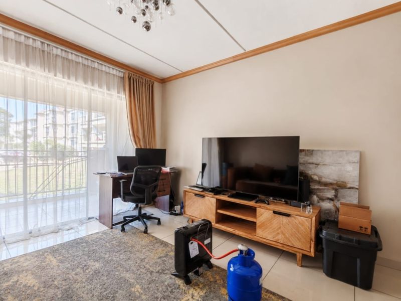 A bright living room featuring tiled flooring and a large sliding glass door that provides access to an outdoor balcony area.
