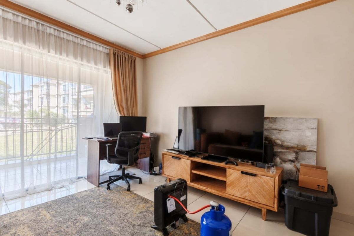 A bright living room featuring tiled flooring and a large sliding glass door that provides access to an outdoor balcony area.