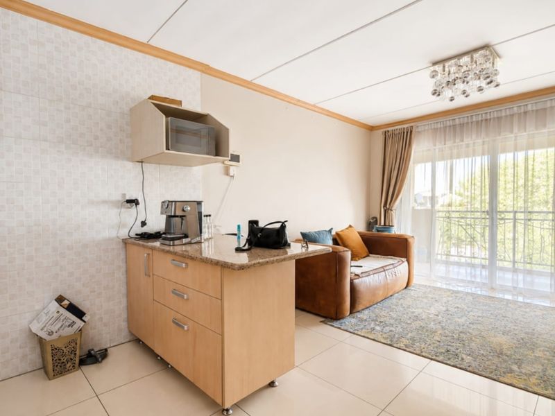 Open plan living area featuring a compact kitchenette with granite countertops, tiled flooring, and direct access to a balcony through sliding glass doors.