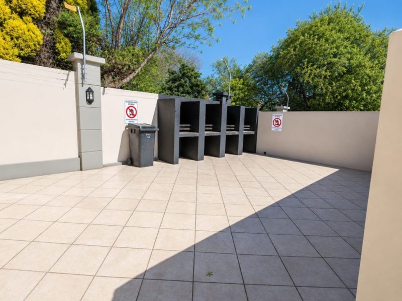 A clean, paved outdoor patio area featuring a row of built-in braai stations and perimeter walling.