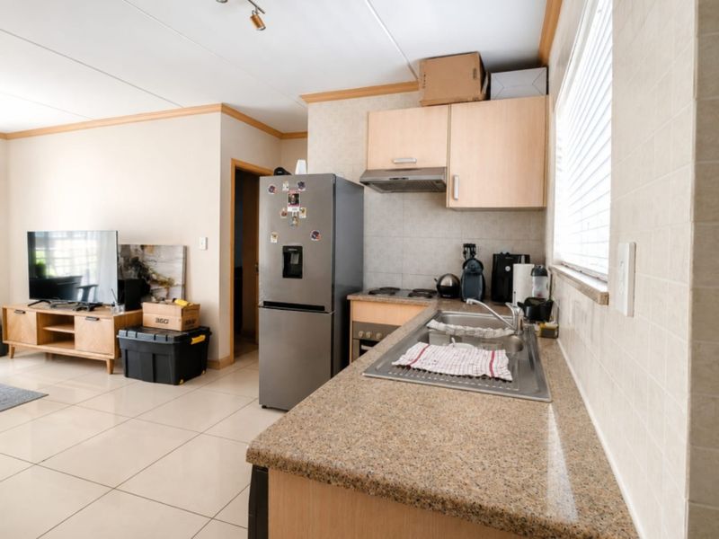 Open-plan kitchen and living area featuring granite countertops, built-in cabinetry, and tiled flooring, offering a functional layout for modern apartment living.