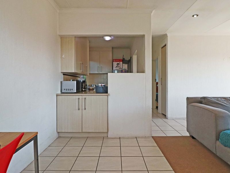Open plan living area featuring a compact kitchen nook with built-in cabinetry and tiled flooring throughout.