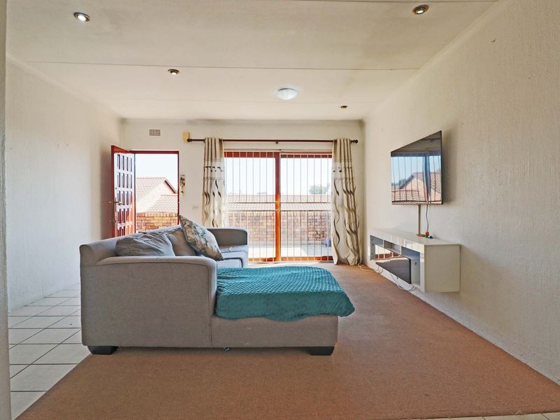 Living room featuring tiled and carpeted flooring, recessed lighting, and a sliding glass door leading to an outdoor balcony area.
