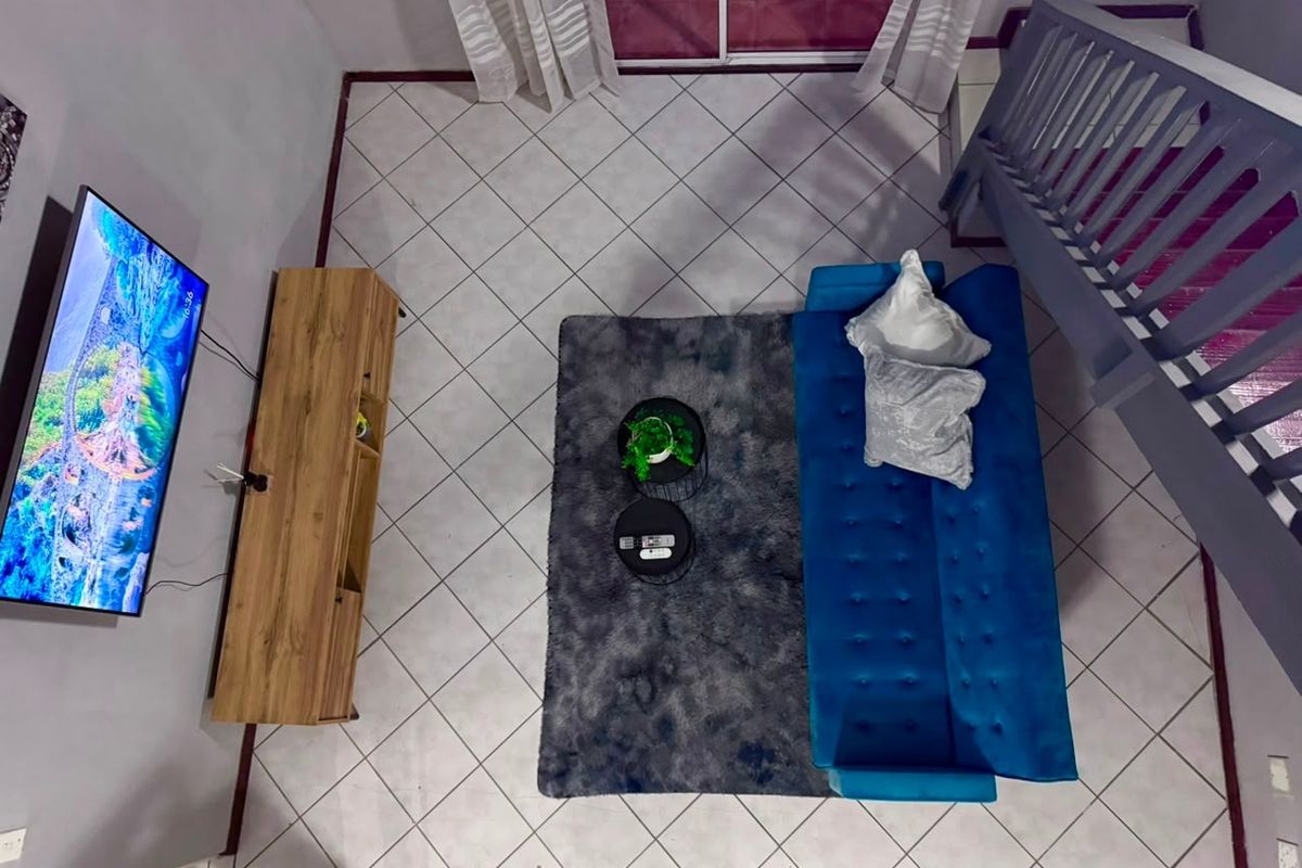 An overhead view of a living room featuring tiled flooring, a staircase with a railing, and access to a sliding glass door.