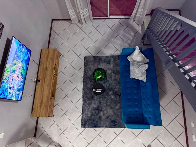 An overhead view of a living room featuring tiled flooring, a staircase with a railing, and access to a sliding glass door.
