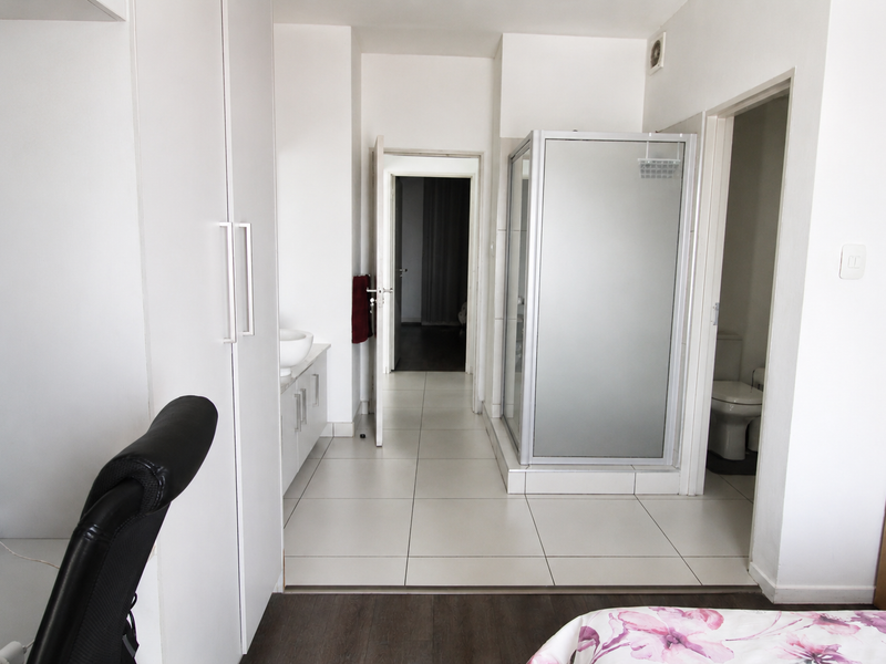 A functional bathroom featuring a shower enclosure, built-in vanity with basin, and a separate toilet area with tiled flooring.