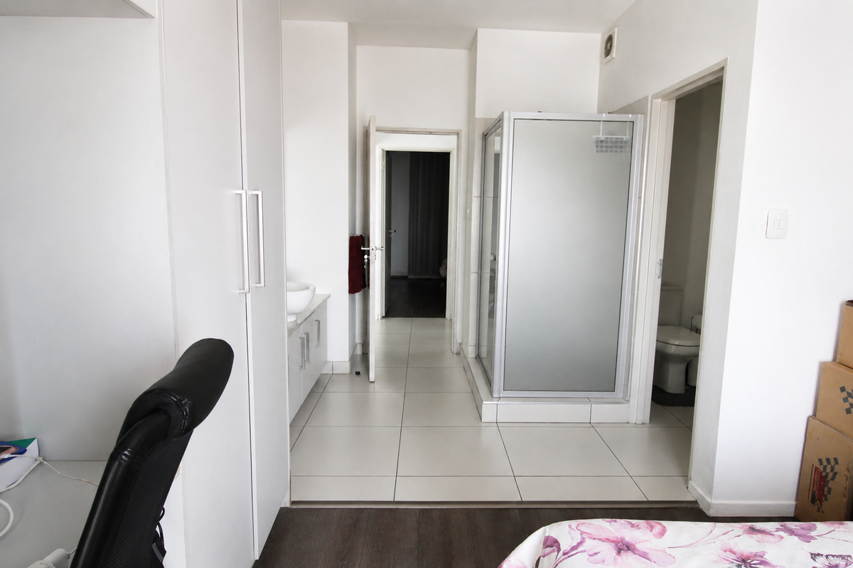 A functional bathroom featuring a shower enclosure, built-in vanity with basin, and a separate toilet area with tiled flooring.