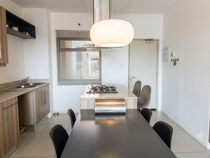 Modern kitchen featuring granite countertops, built-in cabinetry, a gas hob with extractor fan, and tiled flooring in an open-plan layout.