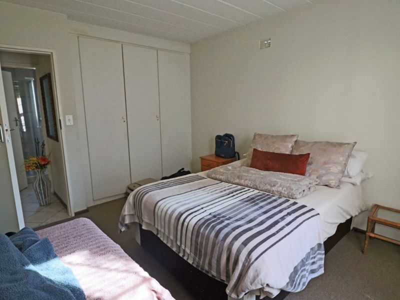A functional bedroom featuring built-in cupboards, carpeted flooring, and direct access to an adjoining bathroom.