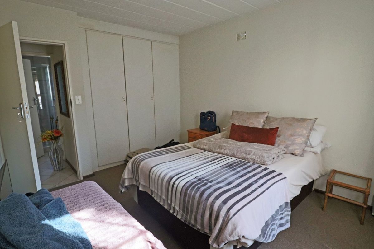 A functional bedroom featuring built-in cupboards, carpeted flooring, and direct access to an adjoining bathroom.