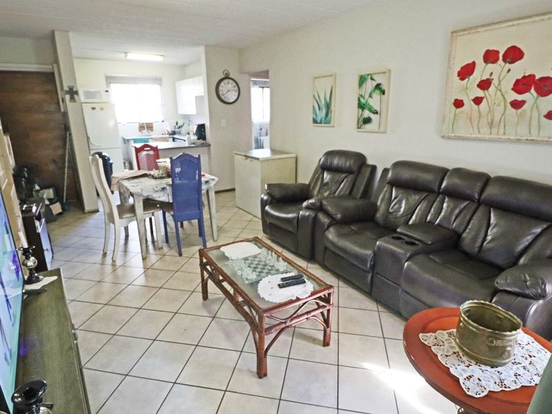 Open-plan living and dining area featuring tiled flooring and a functional kitchen space with built-in cabinetry.