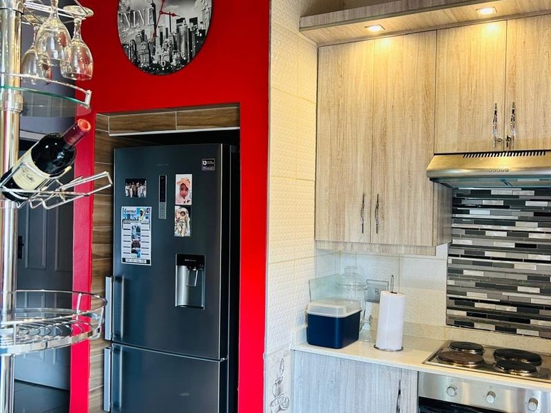 Modern kitchen featuring light wood-grain cabinetry, stone countertops, a mosaic tile backsplash, and integrated stainless steel appliances.