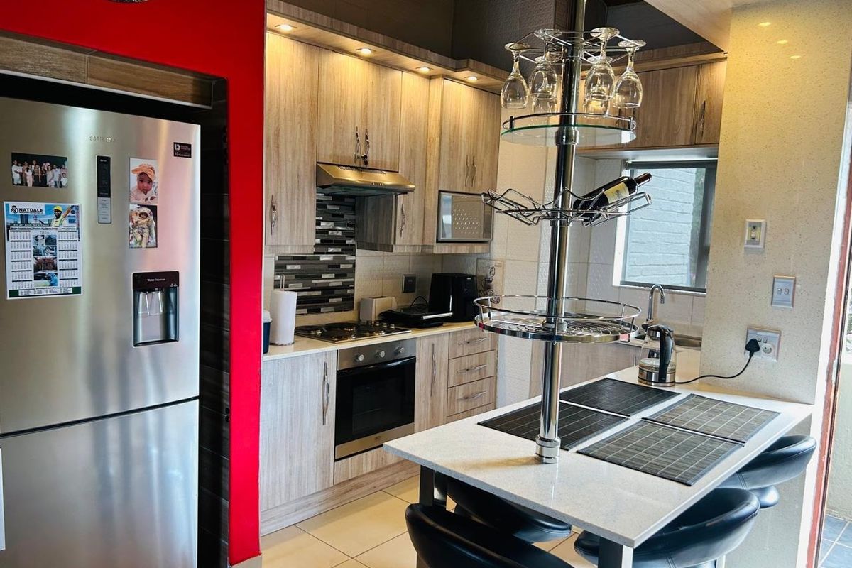 Modern kitchen featuring light wood-grain cabinetry, stone countertops, built-in oven, gas hob, and a breakfast nook with integrated glass storage.