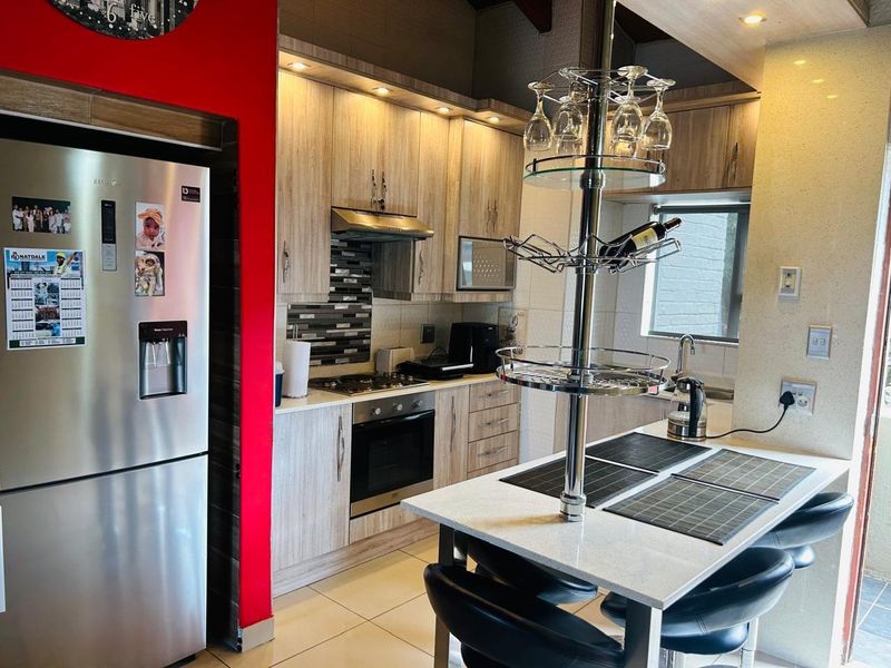Modern kitchen featuring light wood-grain cabinetry, stone countertops, built-in oven, gas hob, and a breakfast nook with integrated glass storage.