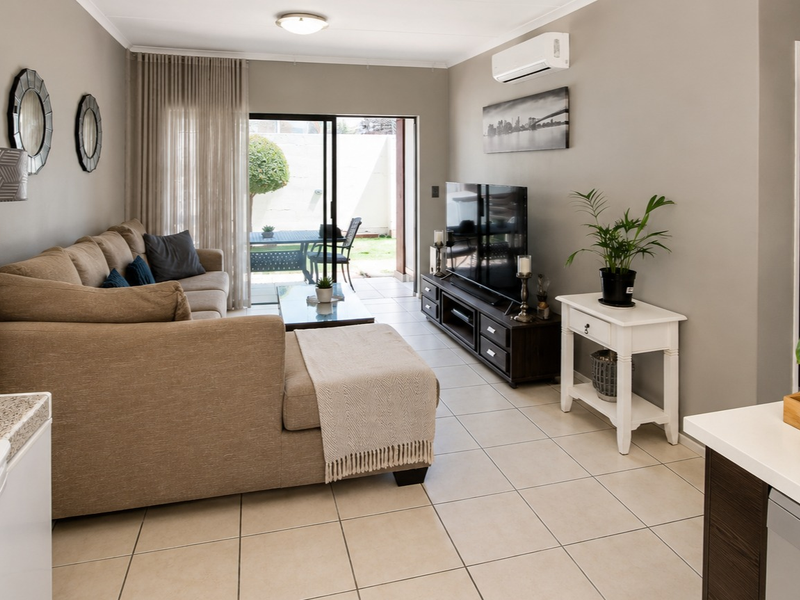 Open-plan living area featuring tiled flooring, a split-system air conditioner, and sliding glass doors providing direct access to the rear patio.