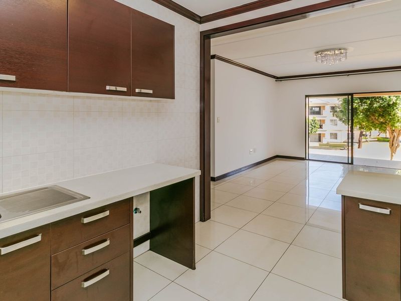 Open plan kitchen and living area featuring dark wood cabinetry, tiled flooring, and a sliding door leading to an outdoor space.