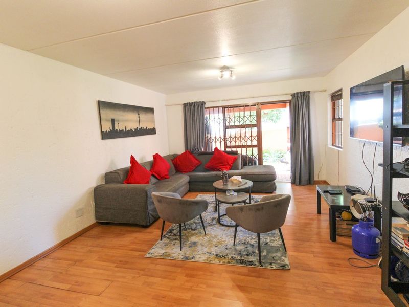A comfortable living room featuring laminate flooring and a sliding door that provides access to the outdoor area through a security gate.