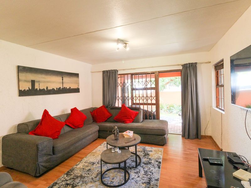 A comfortable living room featuring laminate flooring, a security gate, and a sliding door providing access to the outdoor area.