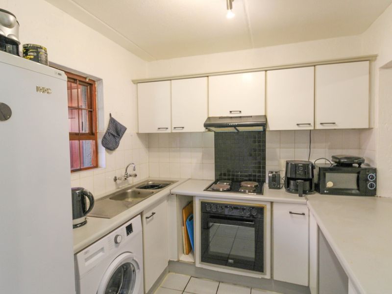 A functional kitchen featuring built-in cabinetry, a stainless steel sink, an electric hob with extractor fan, and a built-in oven.