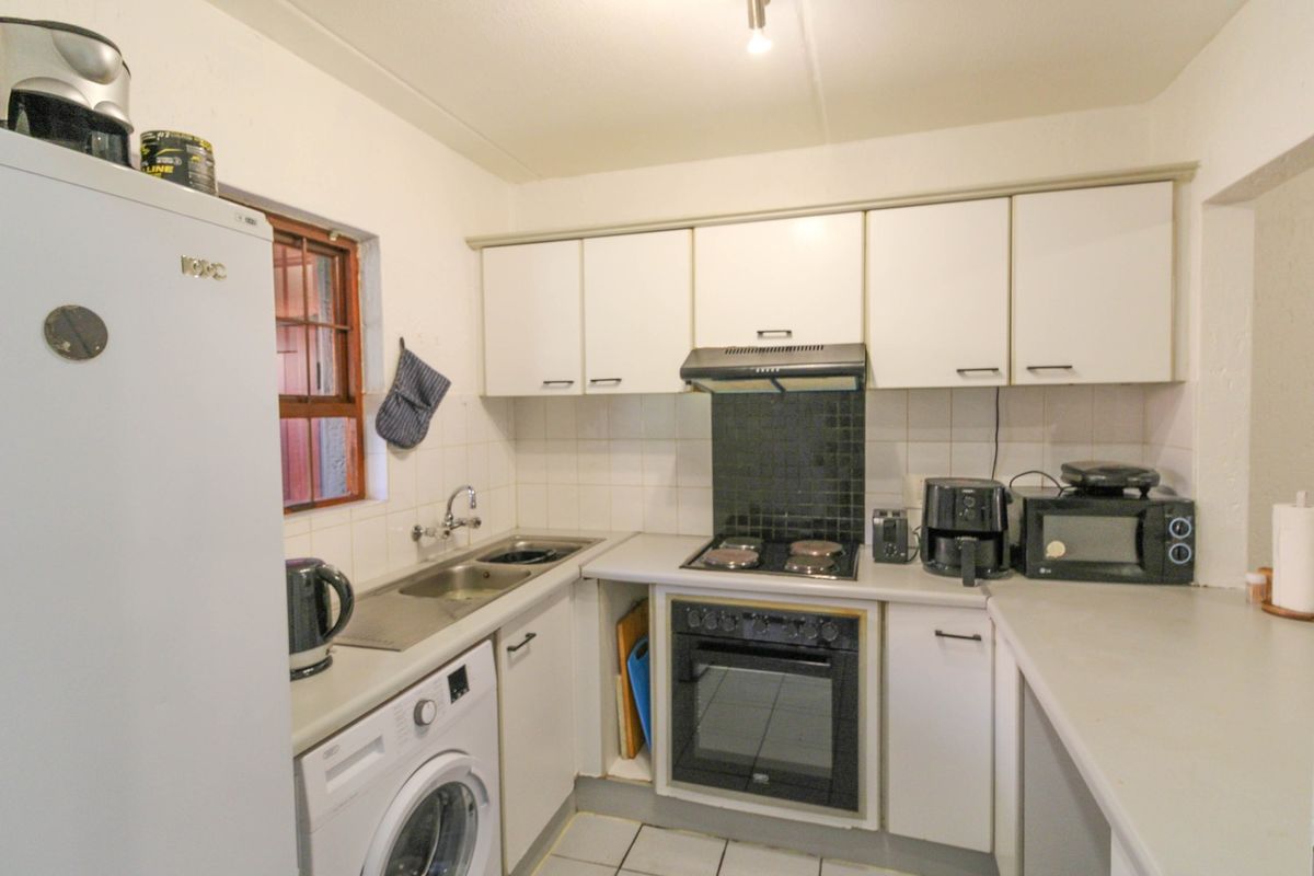 A functional kitchen featuring built-in cabinetry, a stainless steel sink, an electric hob with extractor fan, and a built-in oven.