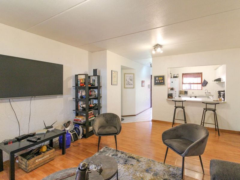 Open plan living area featuring laminate flooring and a breakfast bar connecting to the kitchen space.