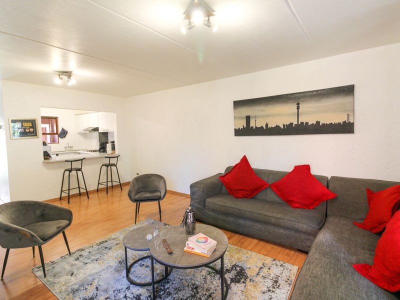 Open plan living area featuring laminate flooring and a breakfast bar connecting to the kitchen space.