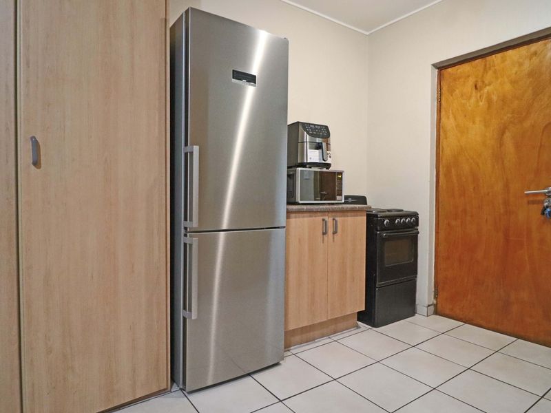 A functional kitchen area featuring tiled flooring, built-in cabinetry, and a freestanding stove, providing essential cooking and storage space.