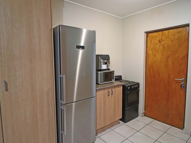 A compact kitchen area featuring built-in cabinetry, a laminate countertop, tiled flooring, and a freestanding stove.