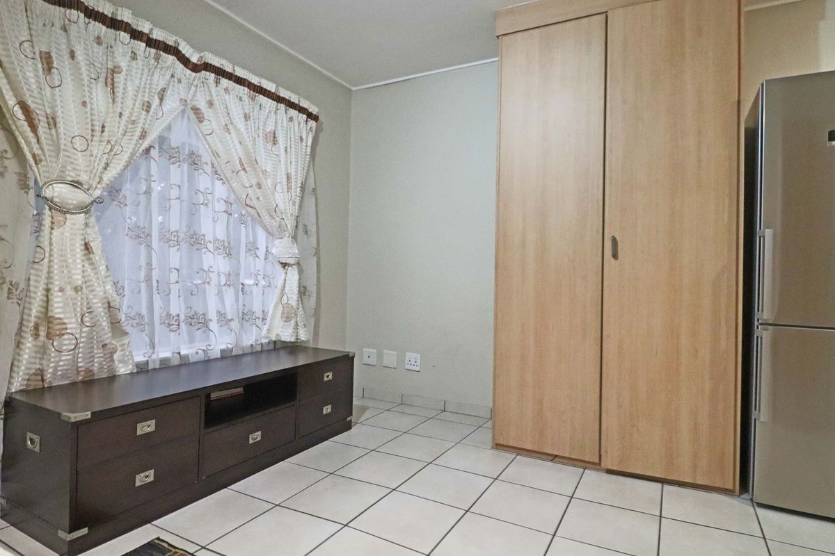 A bedroom featuring tiled flooring and a built-in wooden wardrobe, providing functional storage space.
