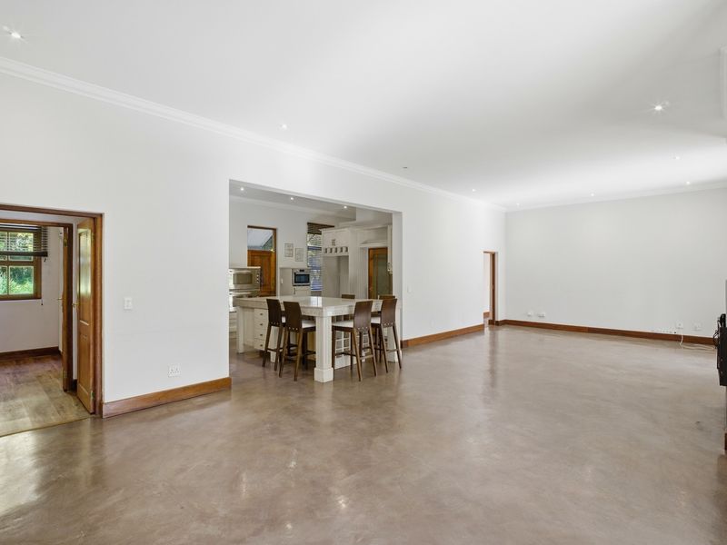 Spacious open-plan living area featuring polished concrete floors, recessed lighting, and a central kitchen island with stone countertops.