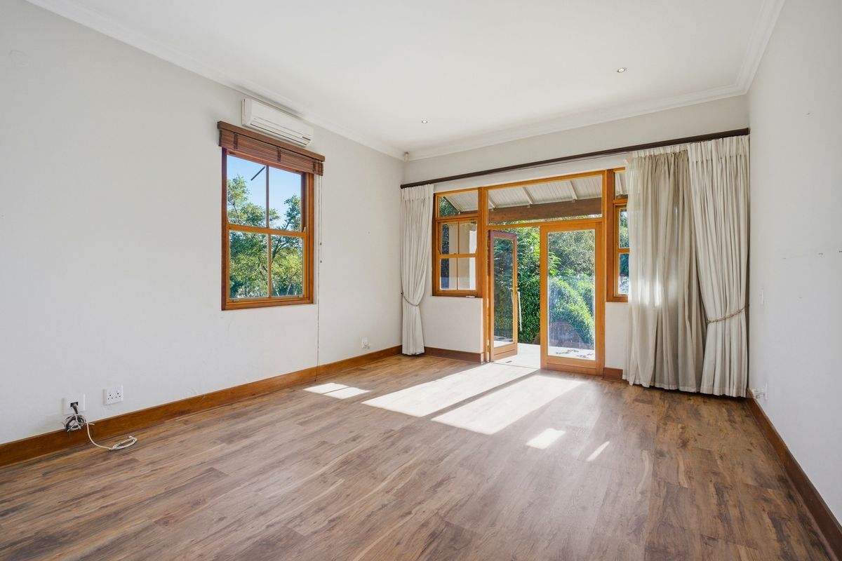 Bright and spacious living area featuring timber-framed windows and doors, laminate flooring, and a split-system air conditioner, with direct access to the outdoor space.