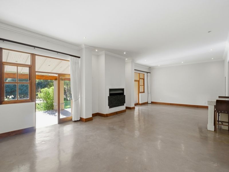 Spacious open-plan living area featuring polished concrete floors, a built-in fireplace, and direct access to a covered outdoor patio.