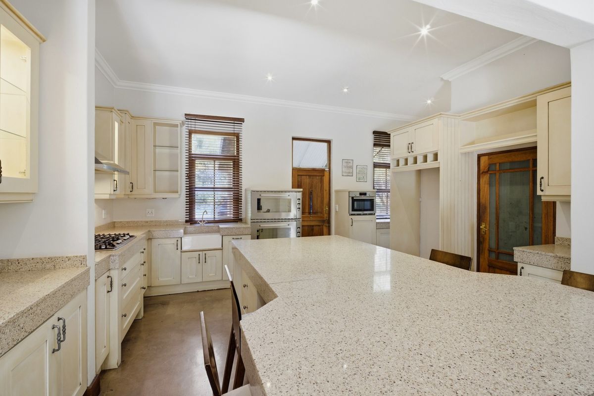 Spacious kitchen featuring stone countertops, a large central island, built-in oven, gas hob, and classic cabinetry with ample storage space.