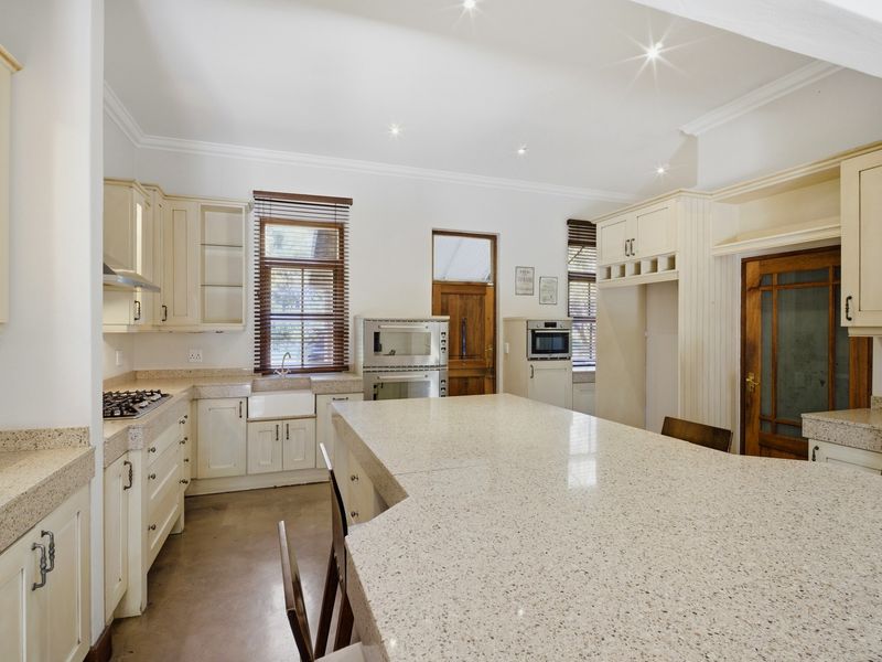 Spacious kitchen featuring stone countertops, a large central island, built-in oven, gas hob, and classic cabinetry with ample storage space.