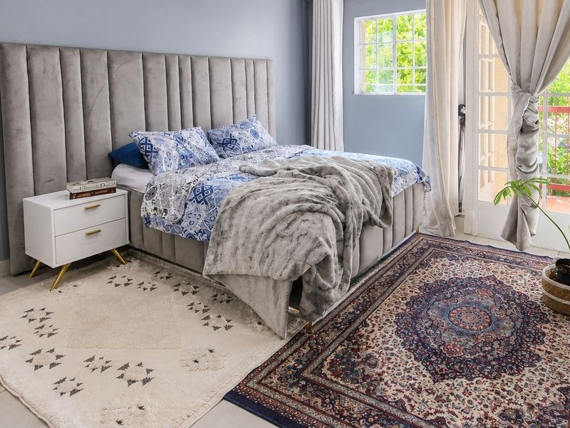 A well-maintained bedroom featuring tiled flooring, a large grid-pattern window, and direct access to an outdoor area through glass french doors.
