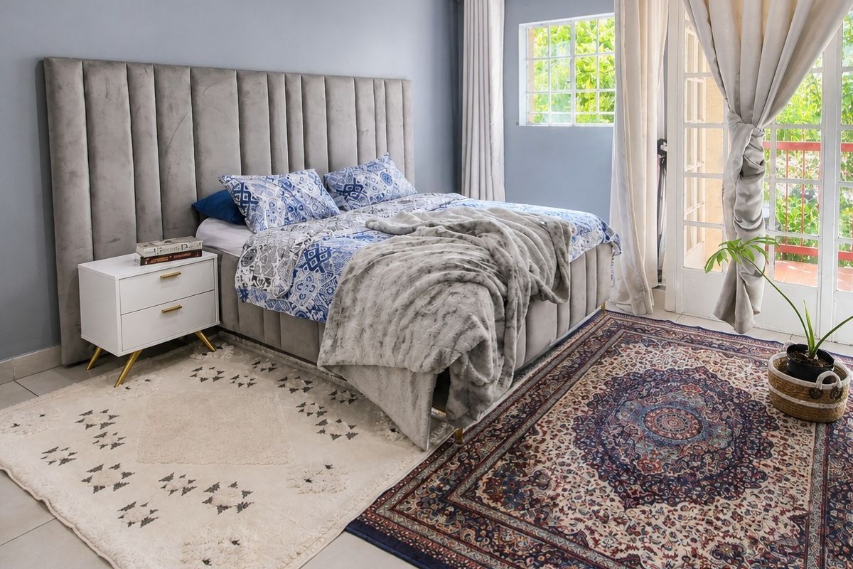 A well-maintained bedroom featuring tiled flooring, a large grid-pattern window, and direct access to an outdoor area through glass french doors.