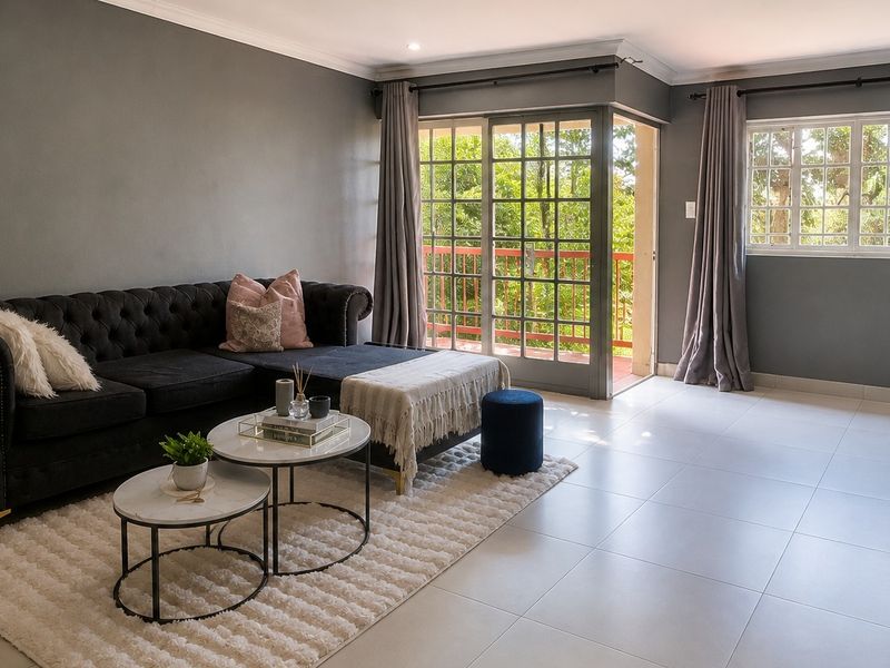 A bright and modern living room featuring neutral tiled floors, recessed lighting, and direct access to a private balcony through sliding glass doors.