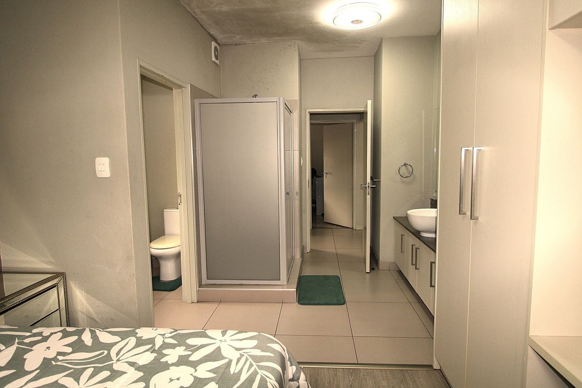 Bathroom featuring a shower enclosure, vanity with vessel sink, built-in storage cupboards, and tiled flooring, showing signs of ceiling water damage.