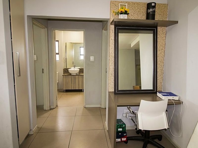 Bedroom featuring tiled flooring, a built-in wardrobe, and a dedicated vanity area, with an adjoining bathroom visible through the doorway.