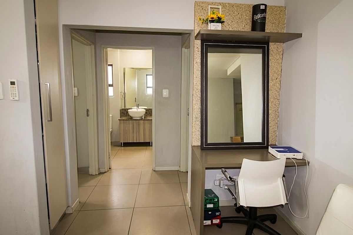 Bedroom featuring tiled flooring, a built-in wardrobe, and a dedicated vanity area, with an adjoining bathroom visible through the doorway.
